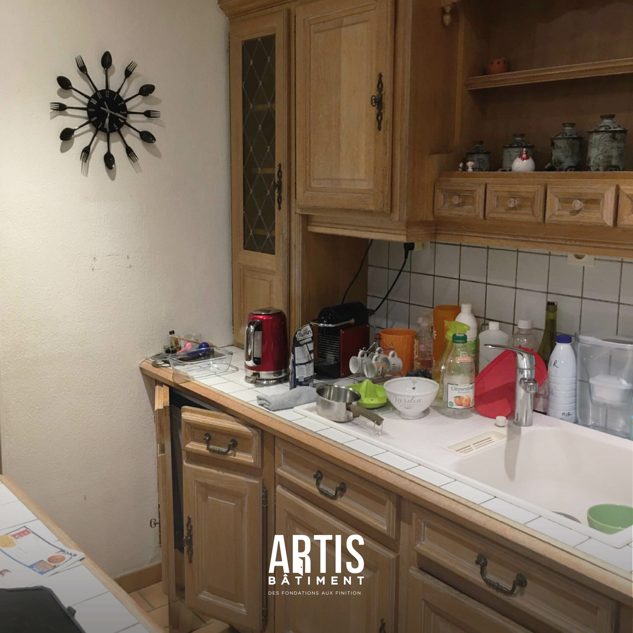 Ancienne cuisine en bois avec plan de travail carrelé et évier avant rénovation.