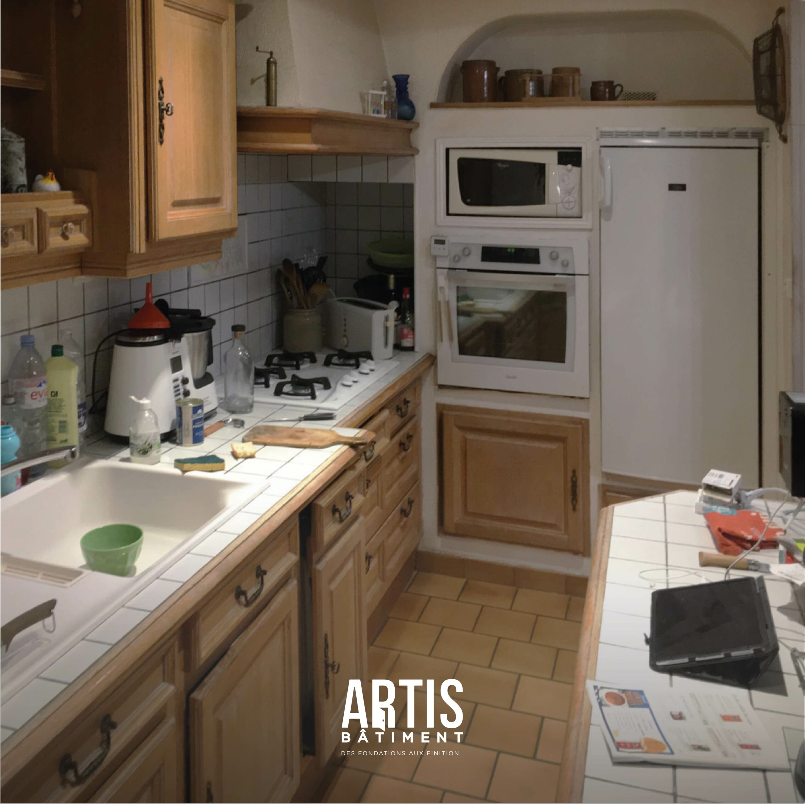 Ancienne cuisine en bois avec plan de travail carrelé et électroménager avant rénovation.