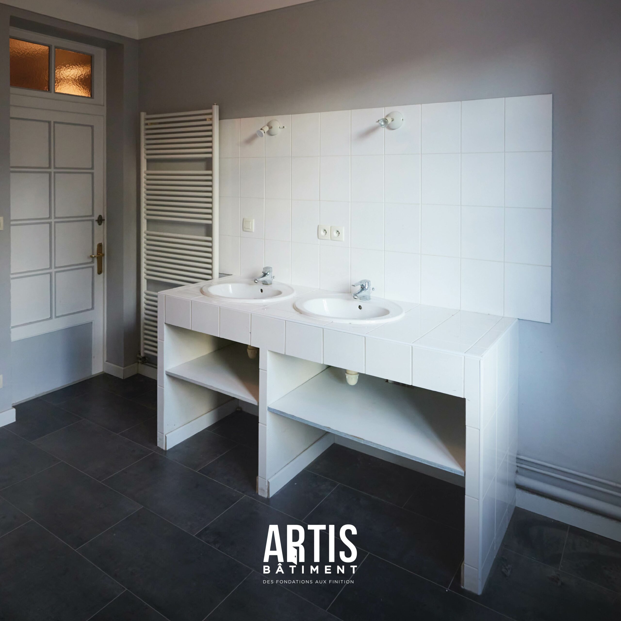 Salle de bain avant rénovation avec meuble double vasque carrelé.