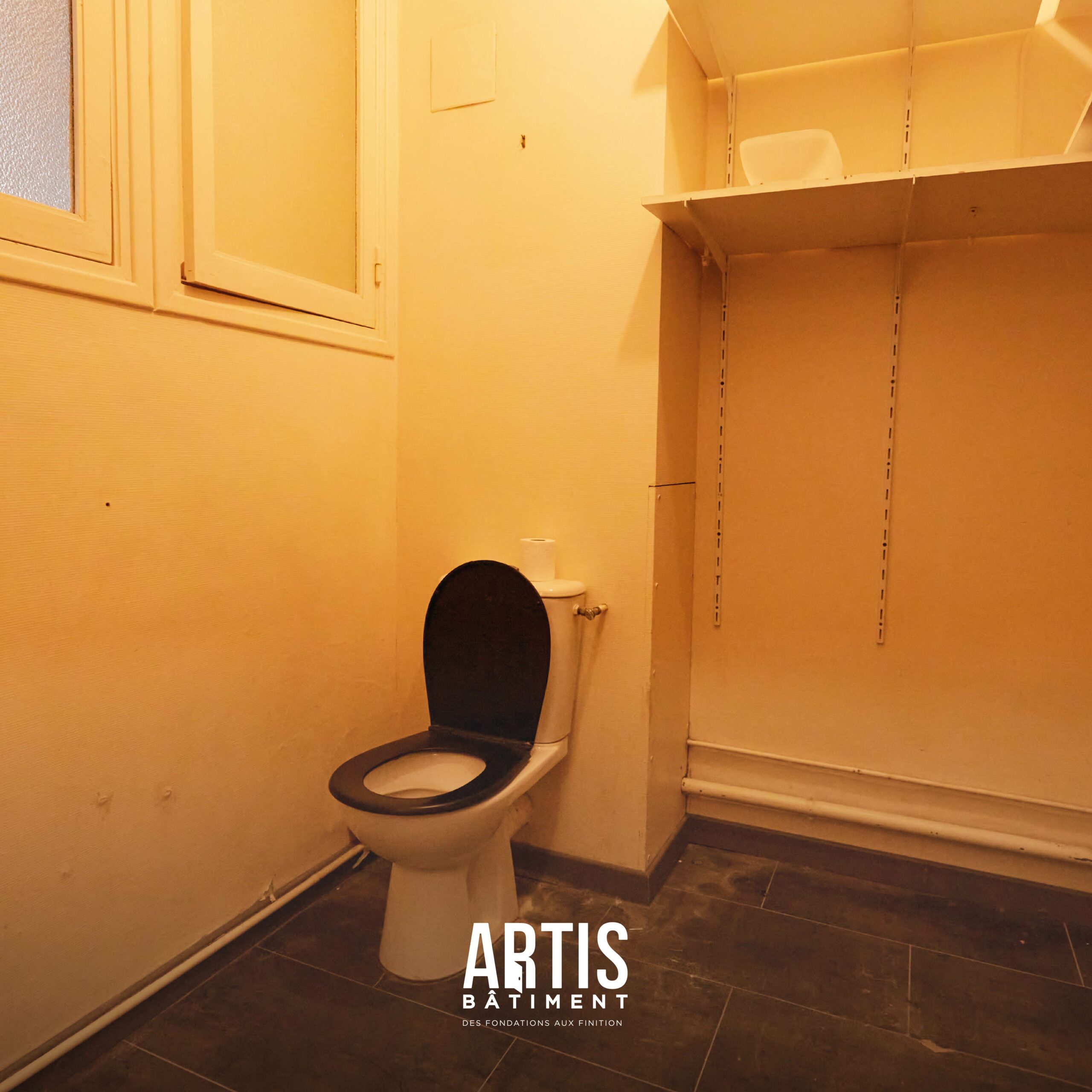 Ancienne pièce WC avec toilettes au sol avant rénovation complète.