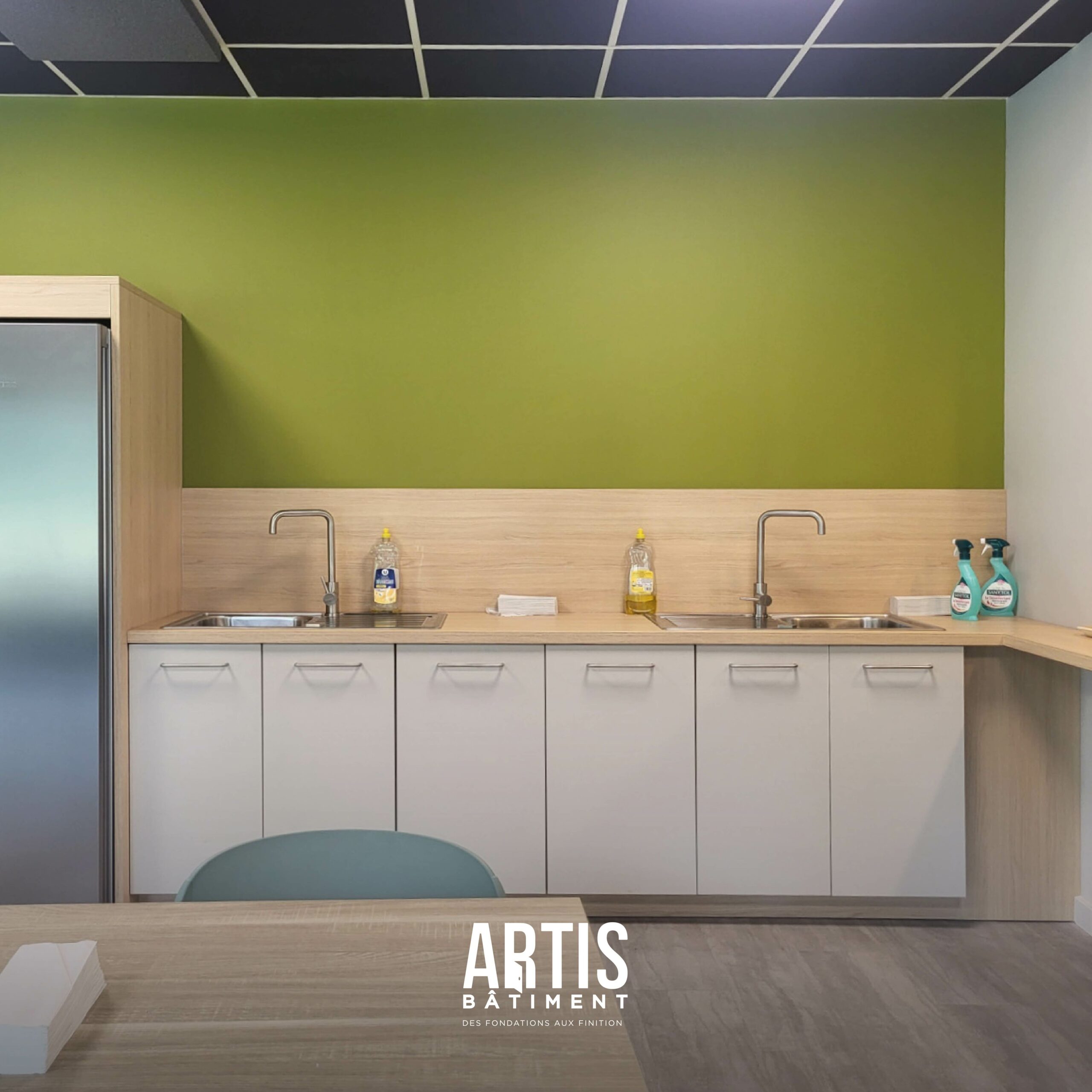 Cuisine rénovée dans une salle de pause d’entreprise avec double évier et meubles modernes.