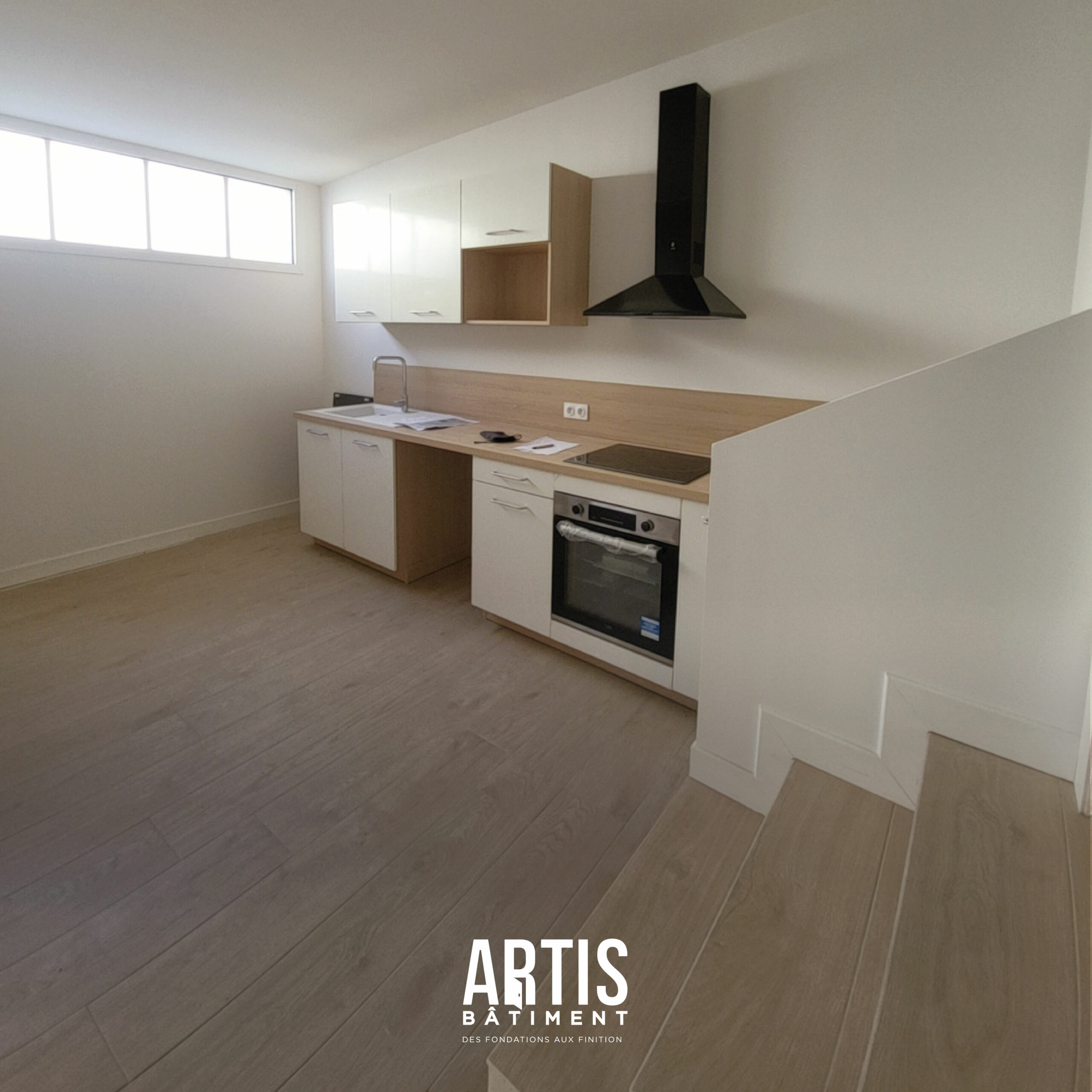 Cuisine moderne blanche et bois avec hotte noire et implantation en angle.