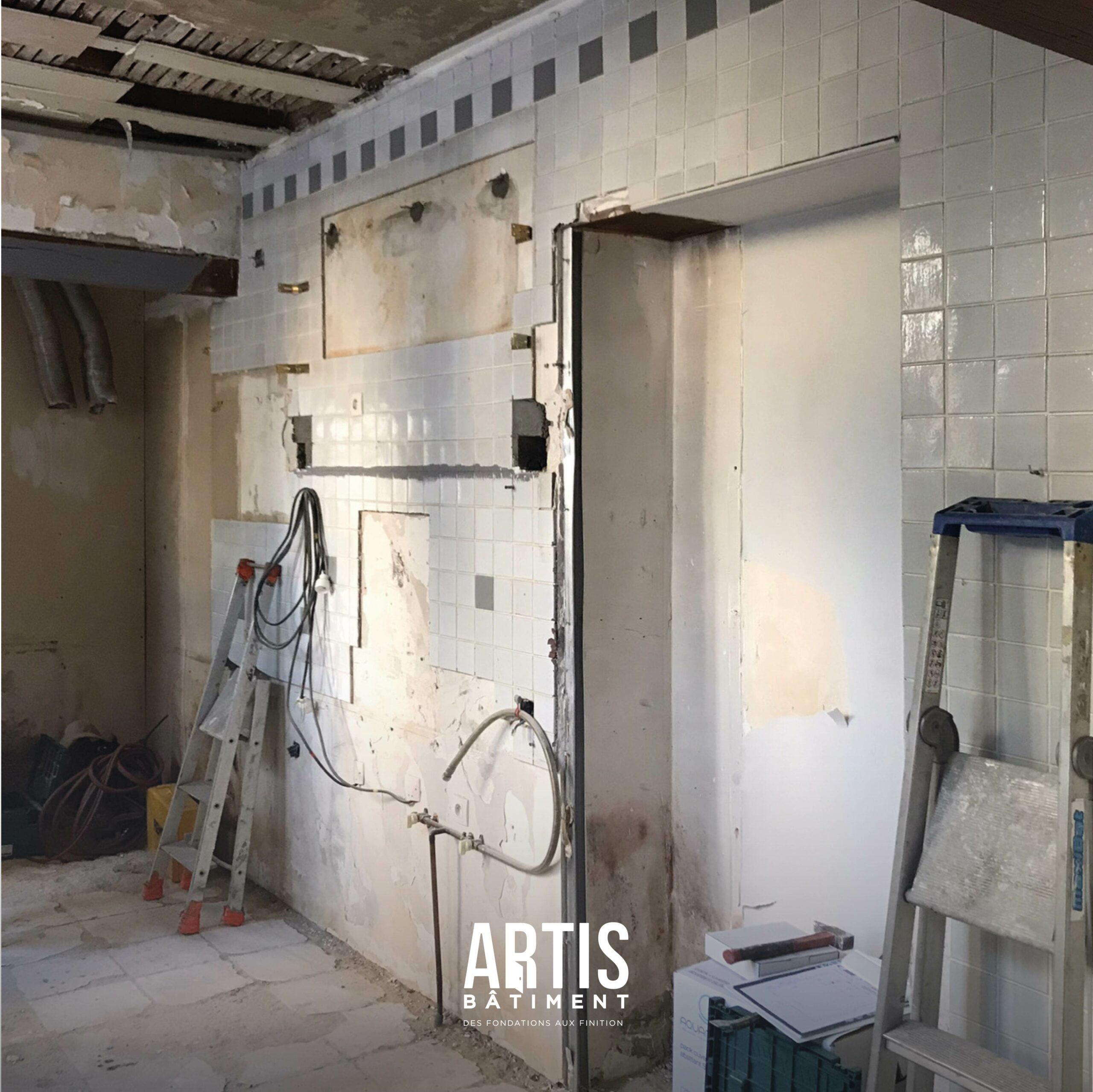 Cuisine en cours de démolition avec murs carrelés et installations déposées avant rénovation.