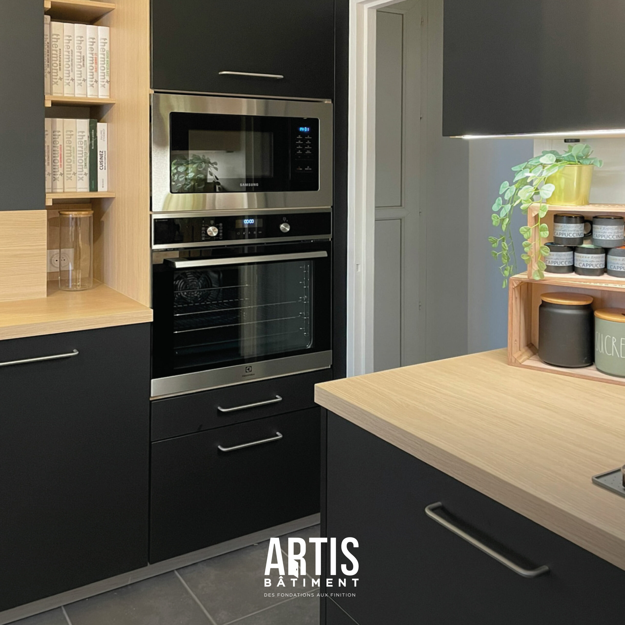 Cuisine moderne noire avec four et micro-ondes encastrés et plan de travail effet bois.