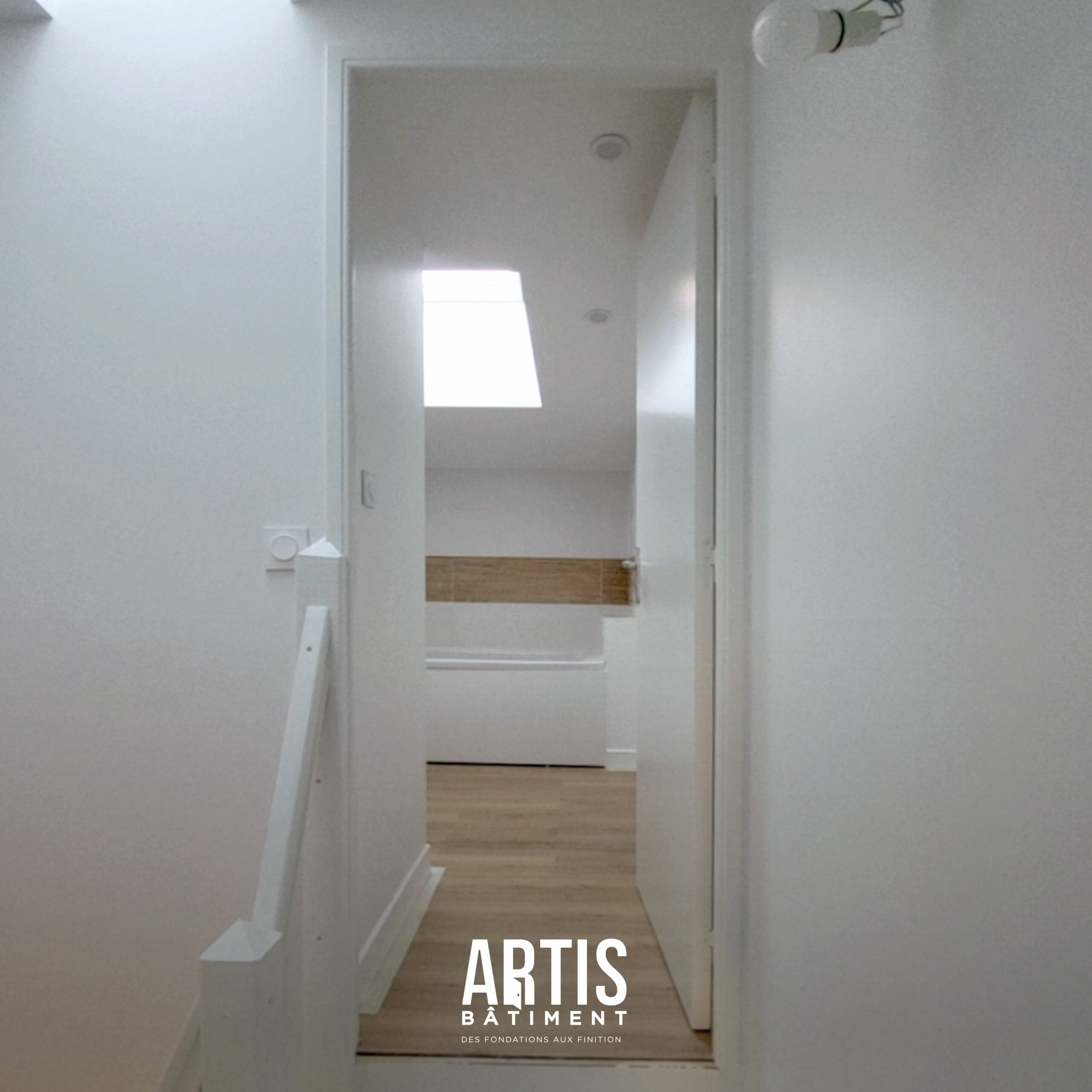 Accès à une salle de bain rénovée avec parquet et éclairage naturel.