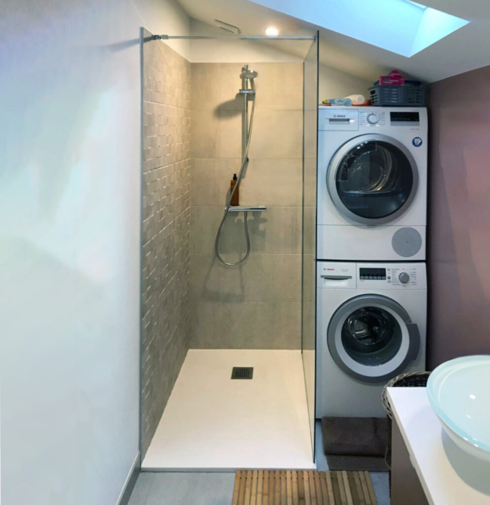 Douche à l’italienne installée sous combles avec colonne lave-linge et sèche-linge intégrée.