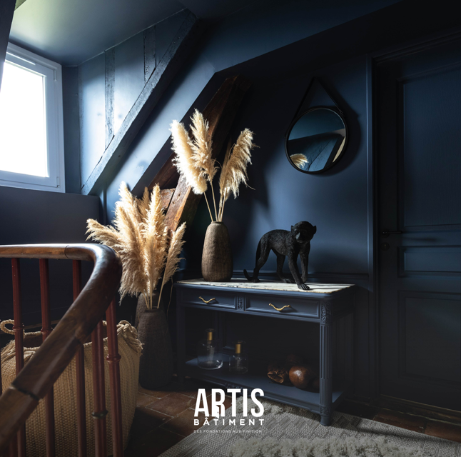 Coin décoration près d’un escalier avec console, vase et miroir dans une maison rénovée.