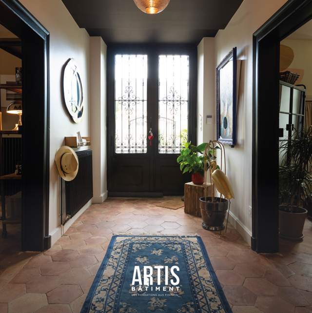 Hall d’entrée rénové d’une maison ancienne avec carrelage hexagonal et porte vitrée.