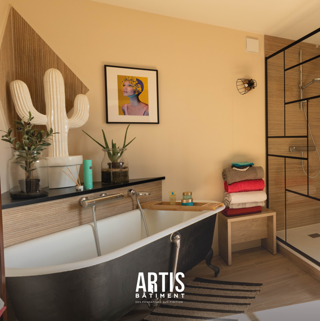 Salle de bain rénovée avec baignoire îlot noire et douche à paroi vitrée.