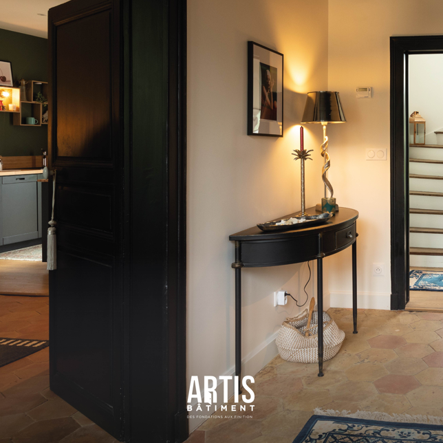 Couloir décoré avec console noire et lampe dans une maison rénovée.