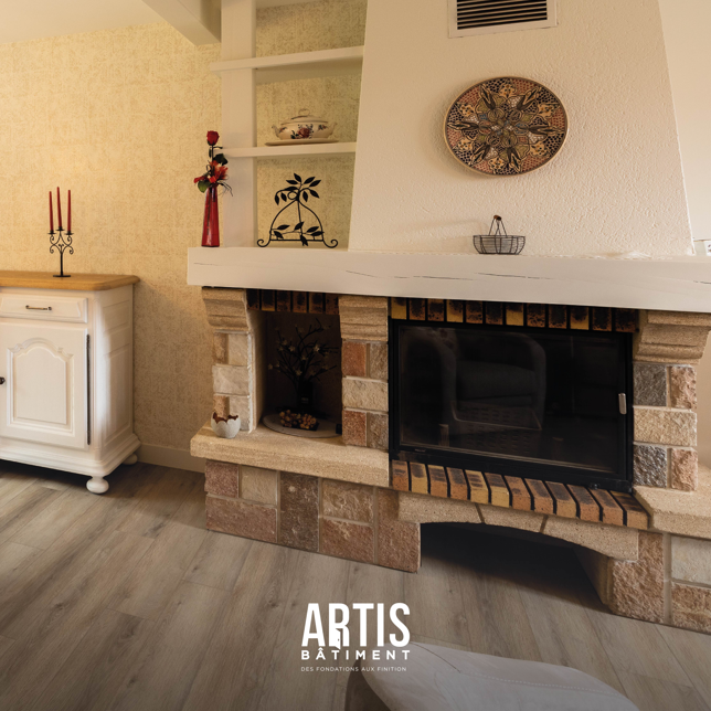 Cheminée rénovée en pierre dans un salon de maison ancienne avec décoration murale.