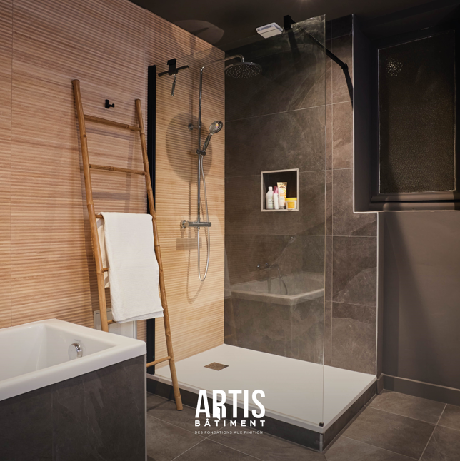 Douche italienne avec paroi en verre et carrelage gris dans salle de bain rénovée.