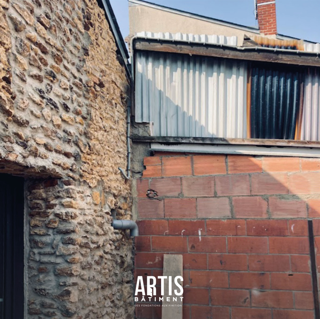 Jonction entre mur en pierre existant et extension en brique avant rénovation extérieure.