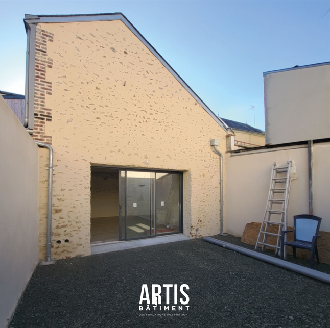 Cour extérieure après rénovation avec façade enduite et portail posé.