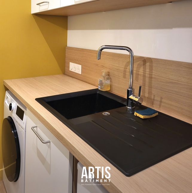 Détail évier noir et plan de travail bois dans cuisine moderne.