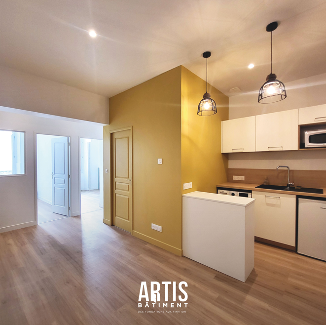 Cuisine ouverte sur le séjour avec mur jaune moutarde après rénovation