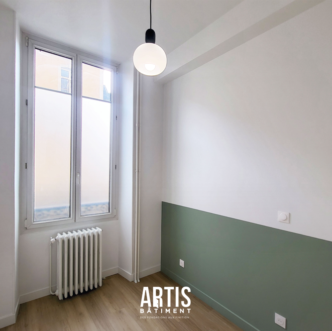 Chambre rénovée avec soubassement vert et fenêtre donnant sur l’extérieur