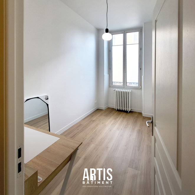 Chambre rénovée avec murs blancs et revêtement de sol effet bois
